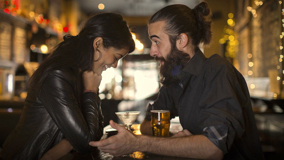 Young couple talking at table with cocktail and beer in public house