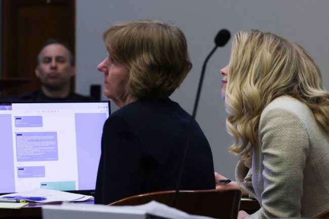 US actress Amber Heard (R) sits at the defense table during her ex-husband Johnny Depp's defamation trial against her, as texts exchanged between the two in 2016 are entered into evidence and displayed on a screen.
