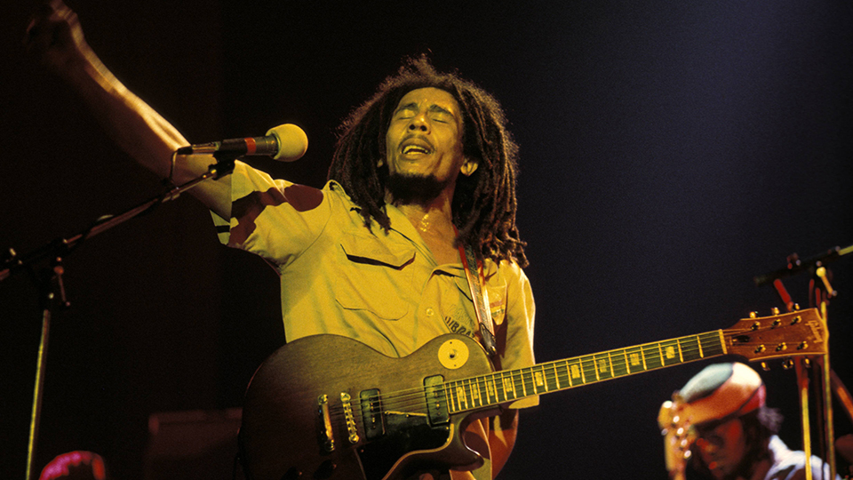 Bob Marley with a guitar performing on stage