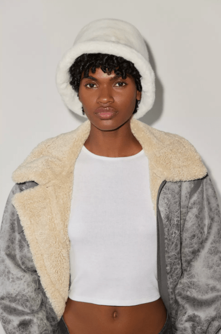 A model wearing a white fuzzy bucket hat from Urban Outfitters
