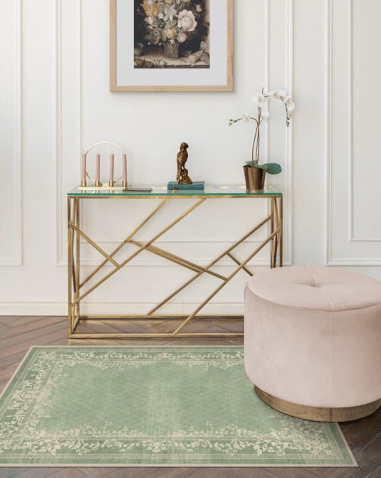 A sage green printed rug in front of a small console table and next to a light pink ottoman
