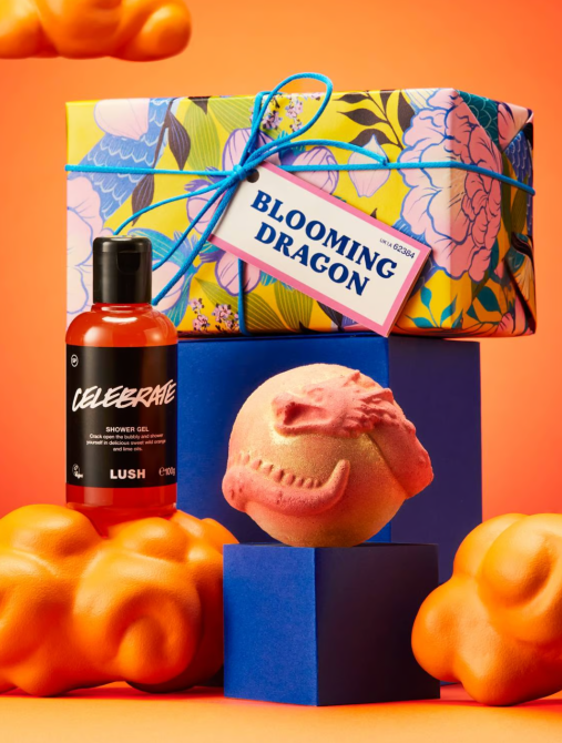 A stack of presents behind a Lush dragon bath bomb and a bottle of shower gel