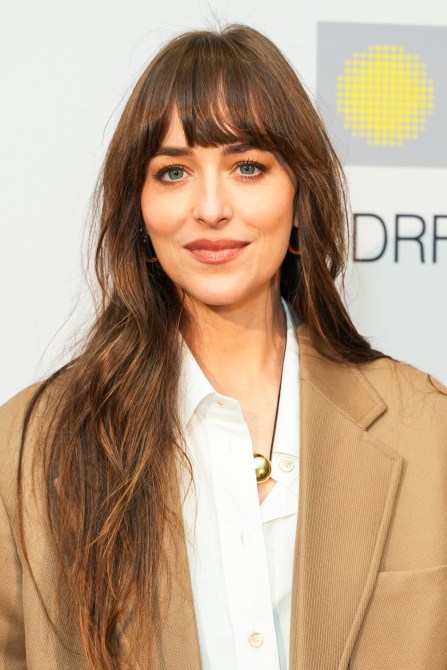 Dakota Johnson wearing a brown coat with bangs.