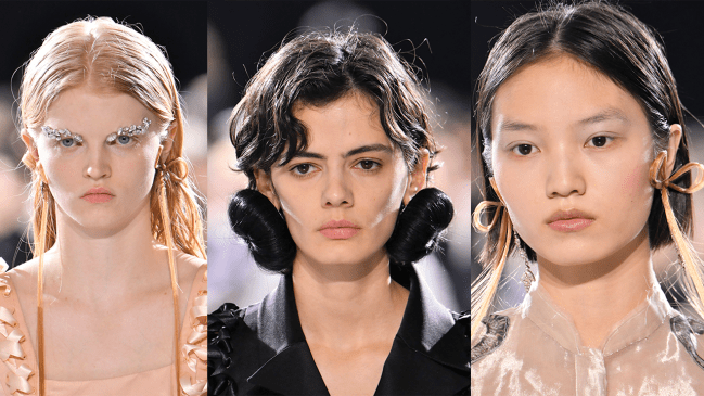 A model wearing bow earrings made of blonde hair, a model wearing hair bun earrings, and another model wearing bow earrings made of blonde hair.