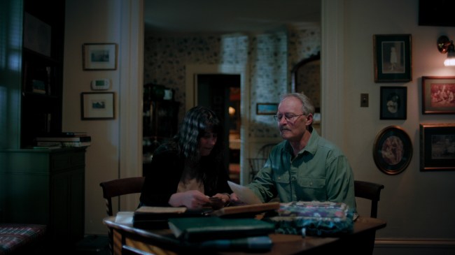 Claudia Huett, Tom Huett. Elderly man and a woman sitting around a table looking at photographs.