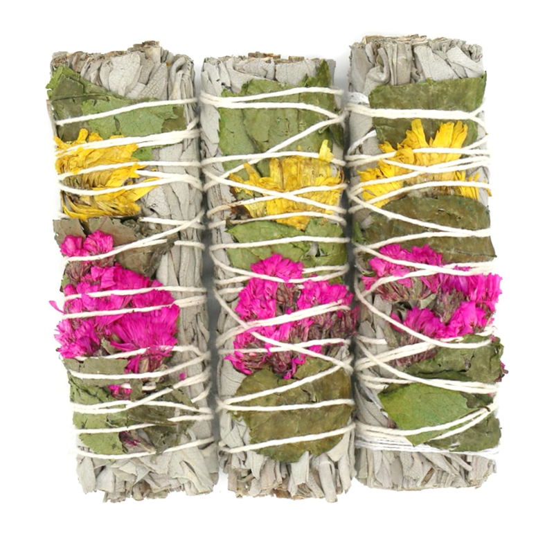 Three bundles of white sage and colorful flowers