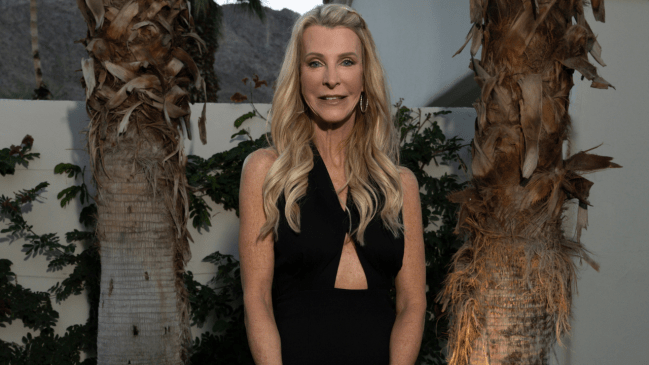 White woman with blonde hair posing in a black dress. Joan Vassos is the first Golden Bachelorette. 