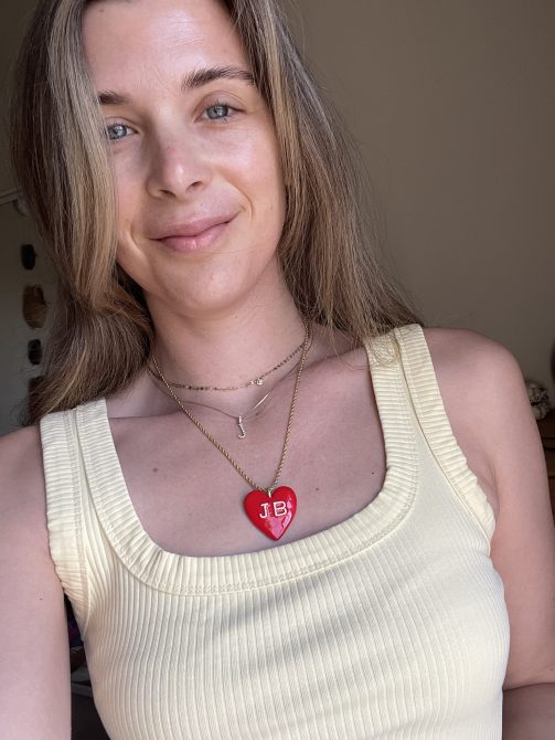woman in a yellow shirt with a red hear necklace on.