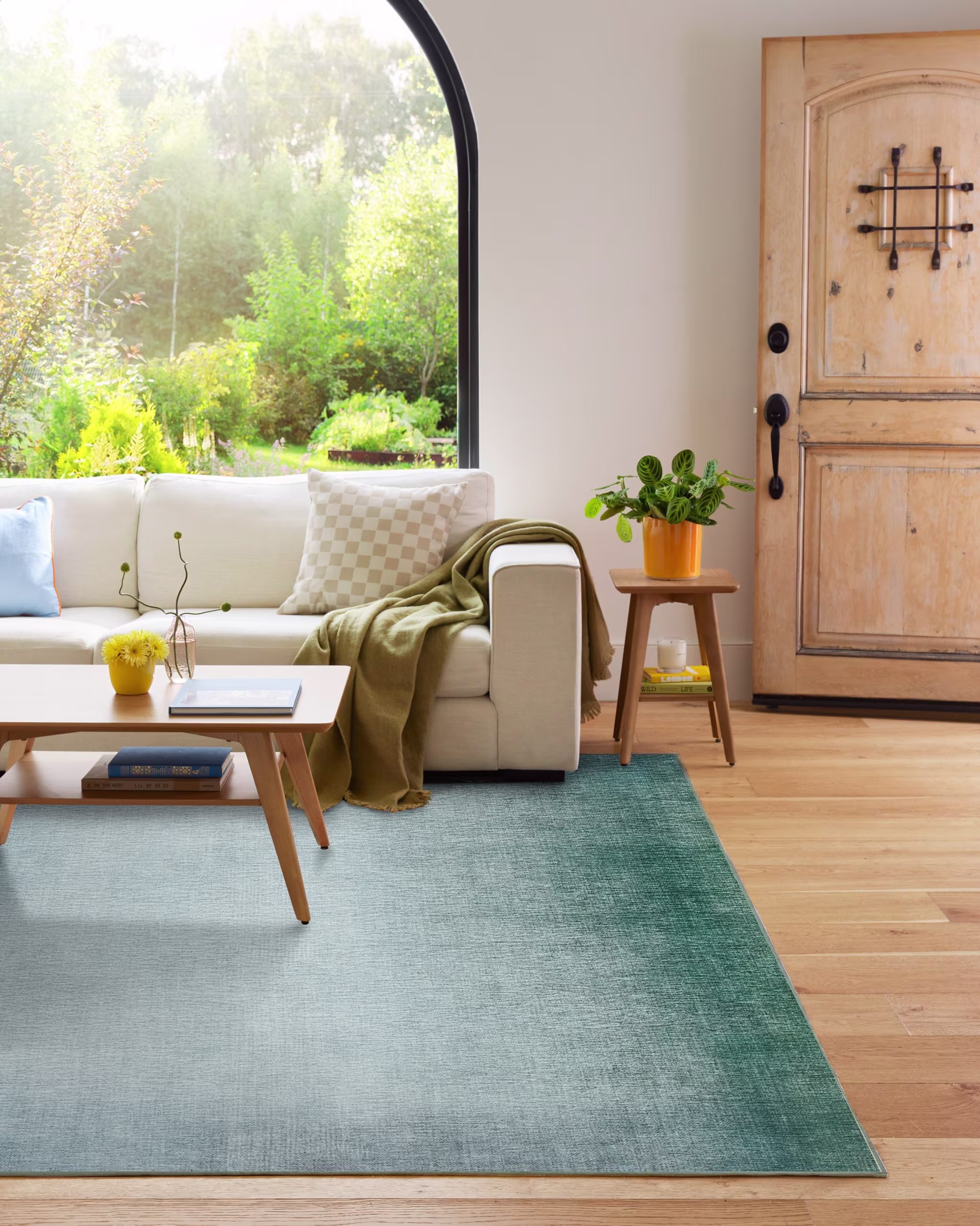 A blue area rug in a living room with a white couch and wooden coffee table on top.