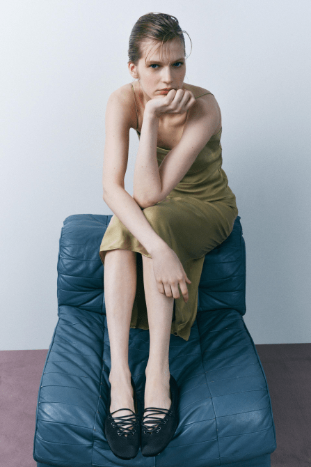 A model wearing a light green midi dress and the Zara Satin Effect Ballet Flats in black
